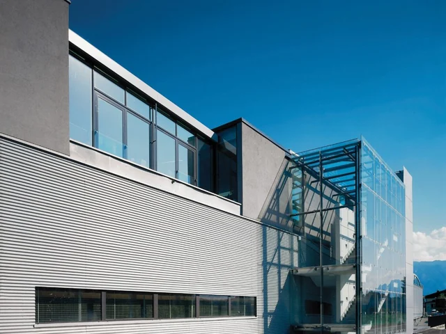 Industriegebäude mit horizontal gegliederter Fassade und verglastem Eingangsbereich.