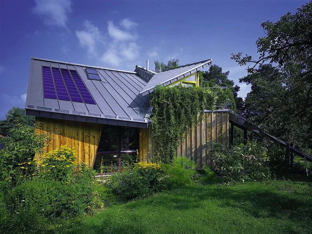 Wohnhaus mit unterschiedlich geneigten Metalldachflächen und Solarmodulen.